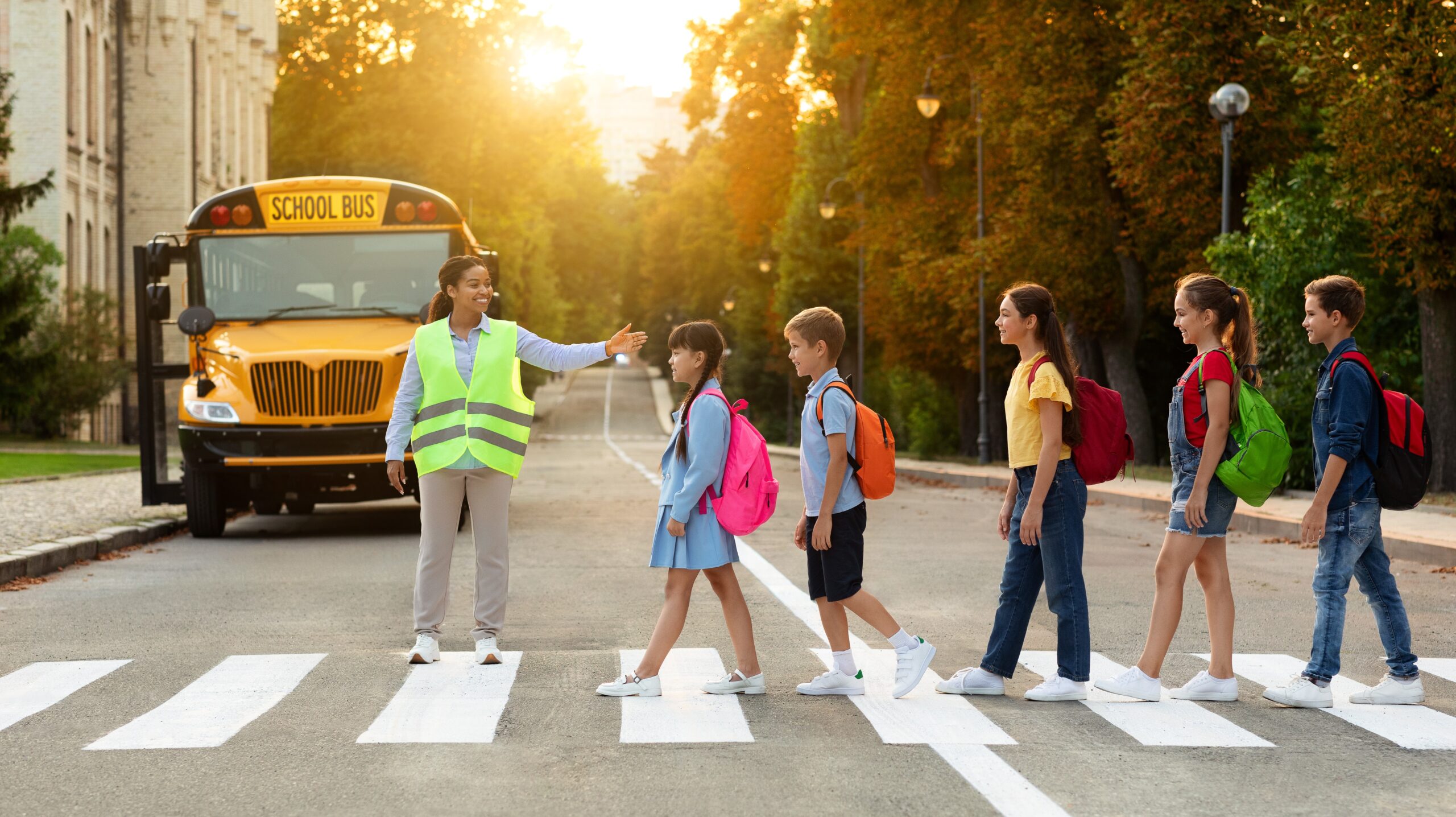 Road Traffic Safety. School Bus Assistant Helping Kids Cross Road By Crosswalk